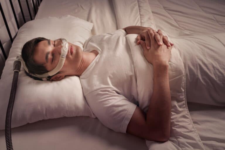A man sleeping with a CPAP machine to manage sleep apnea.